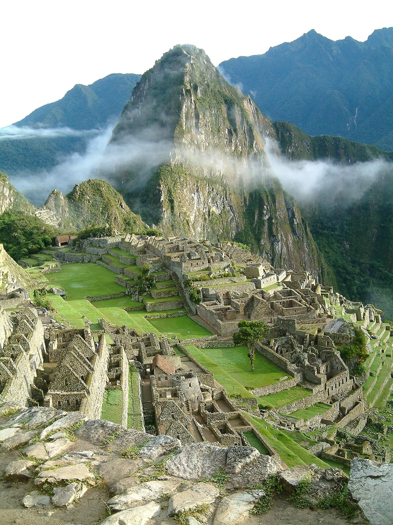 Machu Picchu at sunrise, with Huayna Picchu covered in cloud above the stone terraces.